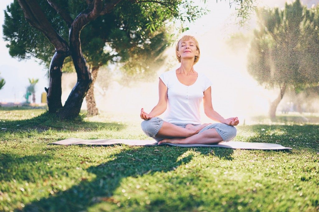 woman meditating on a sunny morning at the park