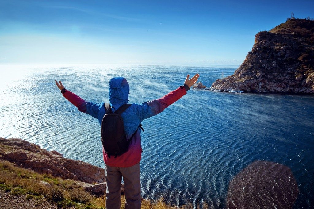 young man standing on a mountain with his arms raised