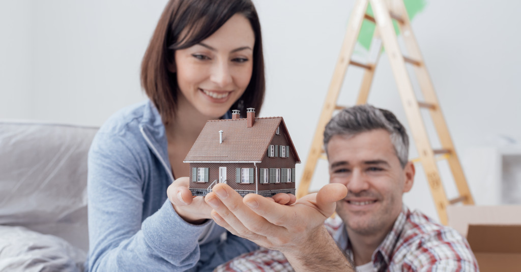 couple holding a scaled down brown house