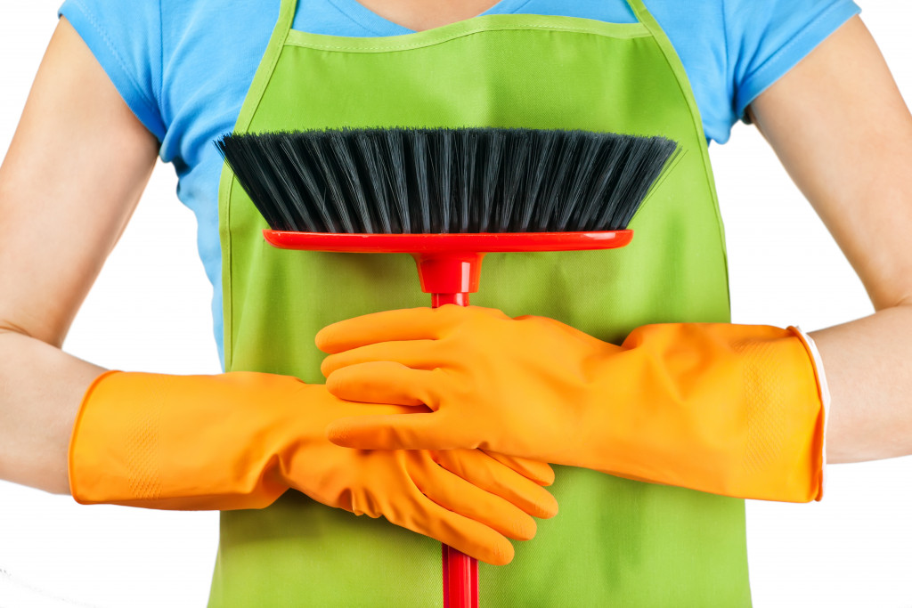 woman holding a brush while wearing gloves and apron