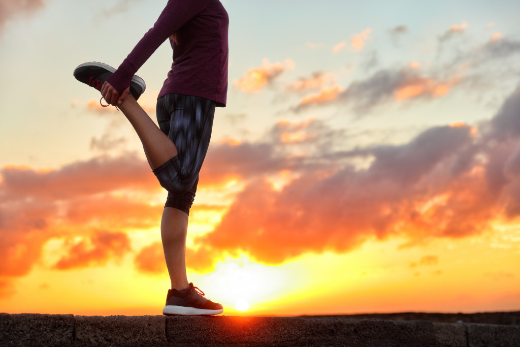 man stretching before going on a run with the sunset on his background