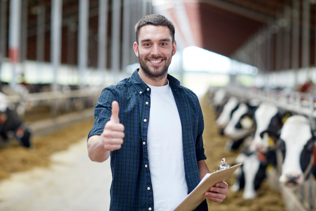 farmer doing a thumbs up with cows behind him