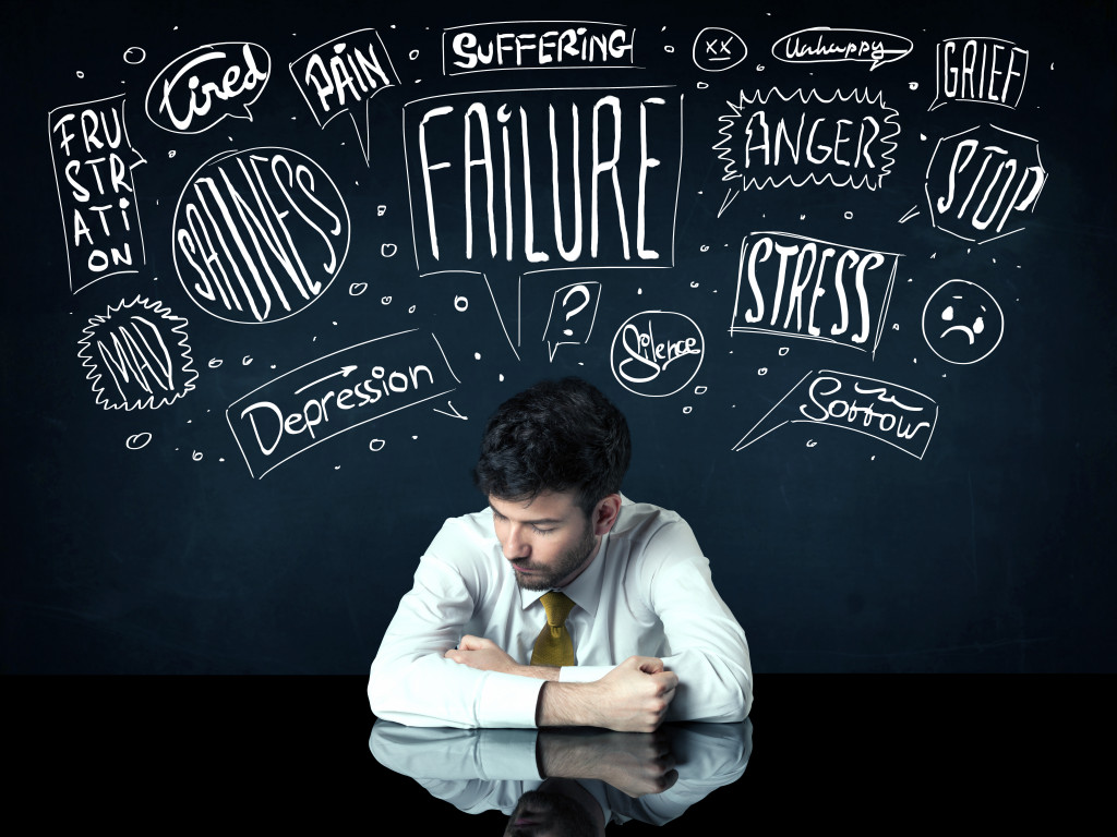 a depressed man sitting under white drawn trouble thought boxes