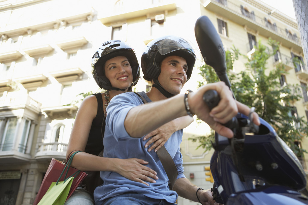 Smiling young couple on a road trip using a scooter.