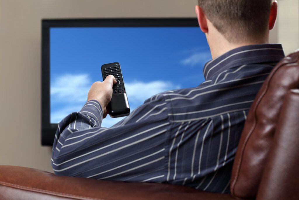 man sitting on a sofa while watching tv