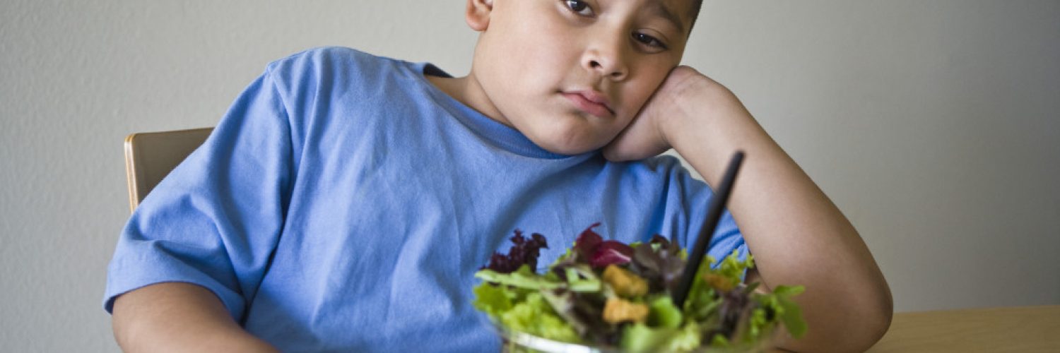 Obese child avoiding salad