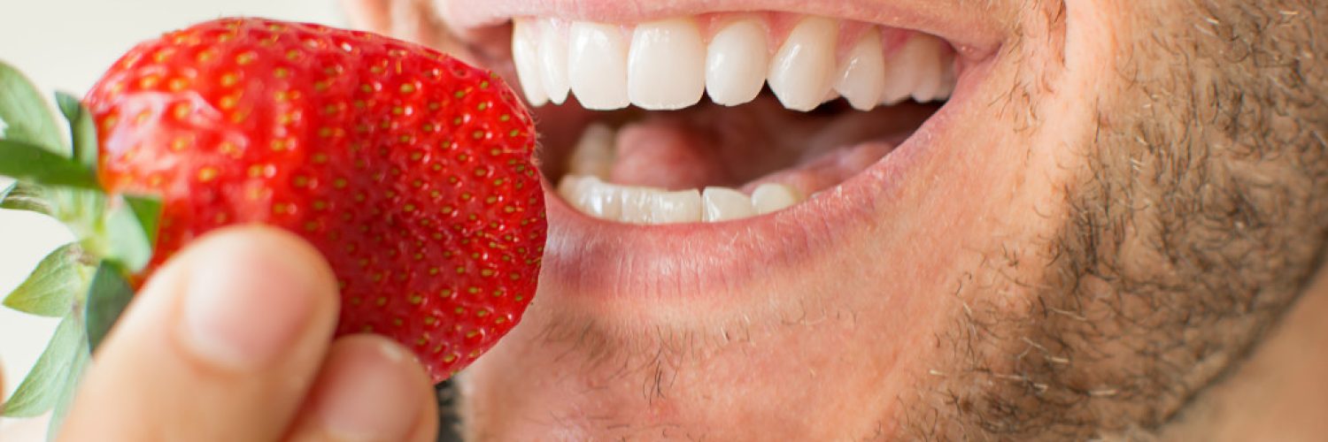 Closeup of a young man eating a strawberry