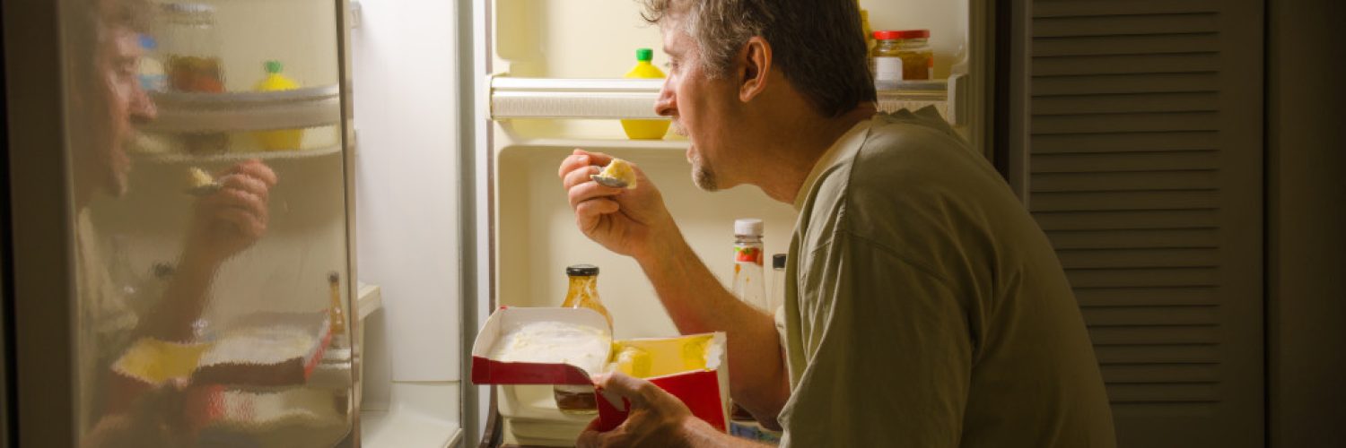 man eating infront of fridge